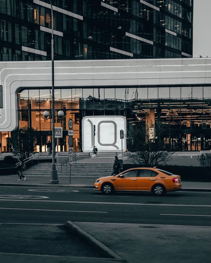 Contemporary architecture with an orange car on a city street, showcasing urban life.