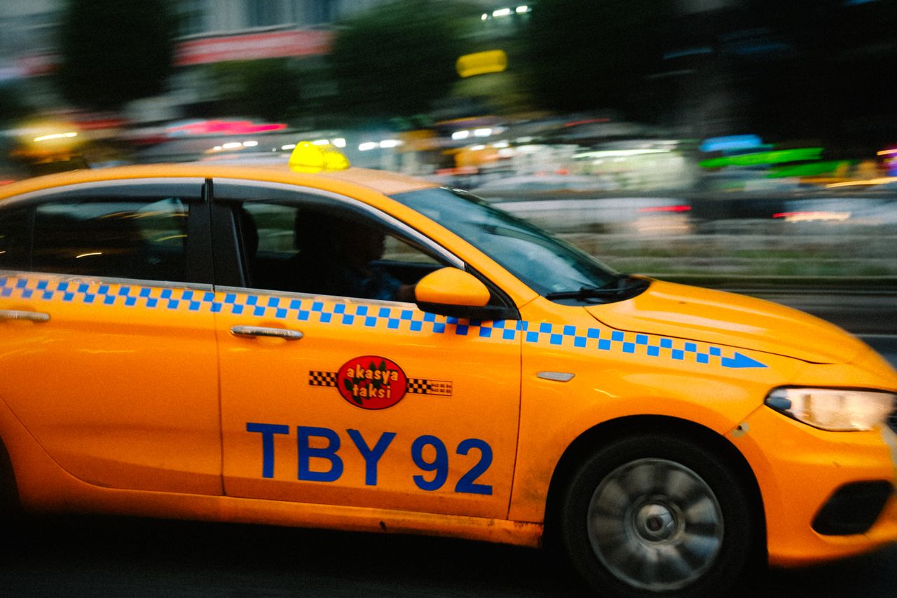 A motion blur shot of a yellow taxi speeding through a city street at night, conveying urban hustle.