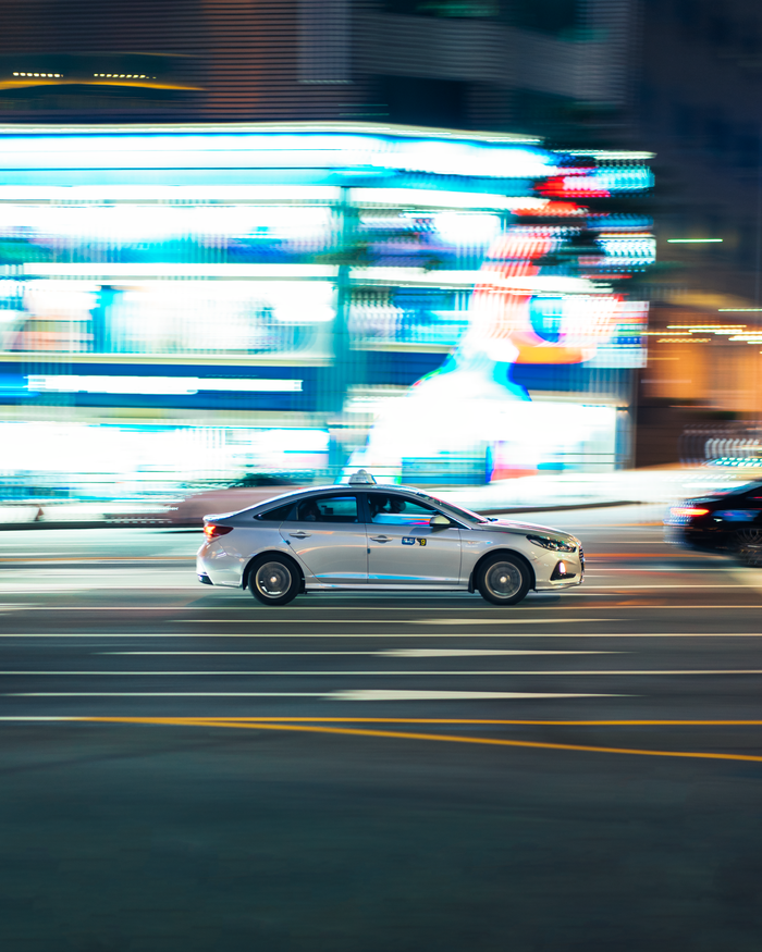 Blurry motion of a taxi speeding through Seoul at night, capturing the city's vibrant nightlife and bustling streets.