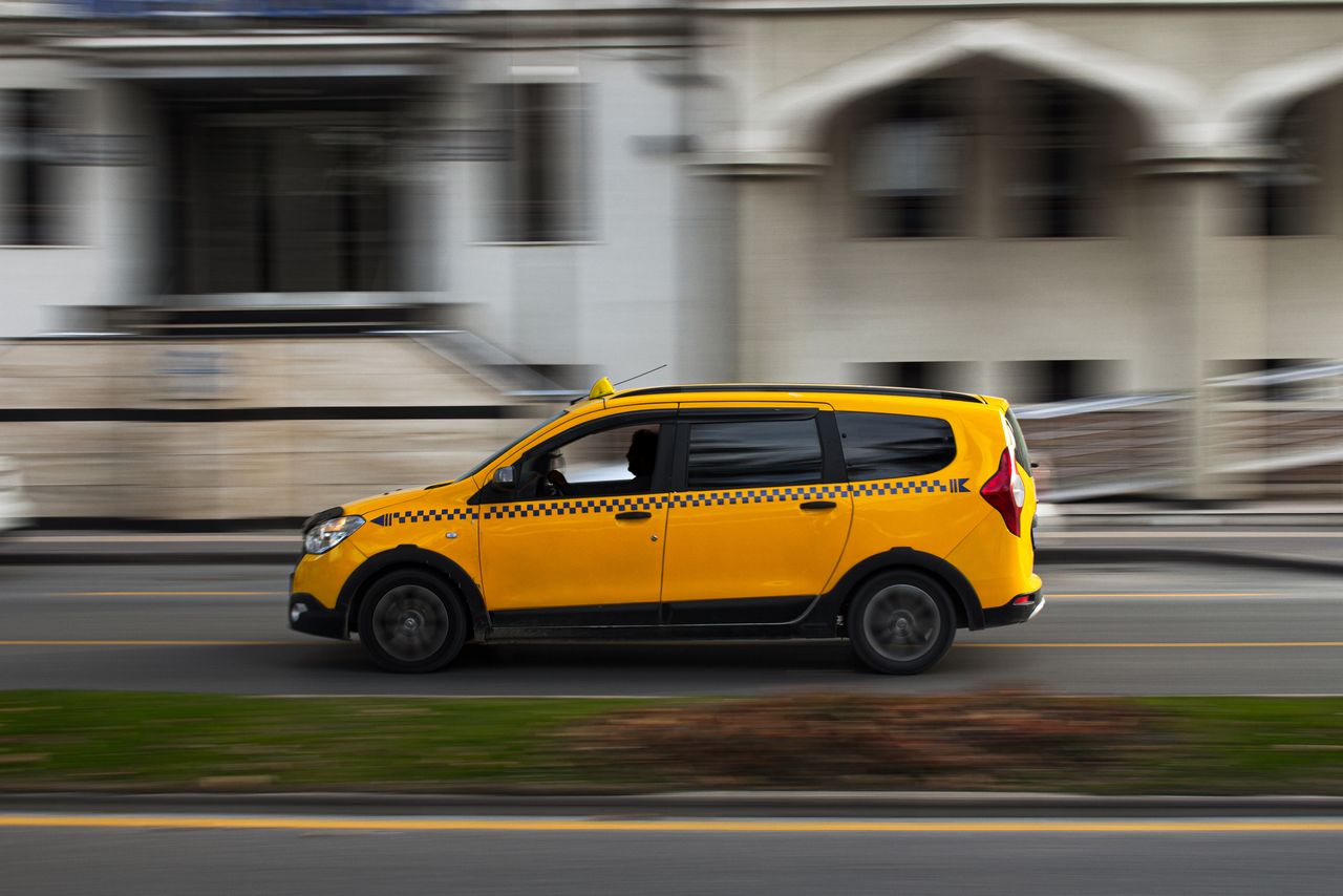 A yellow taxi in motion on a city road, showcasing dynamic urban travel.