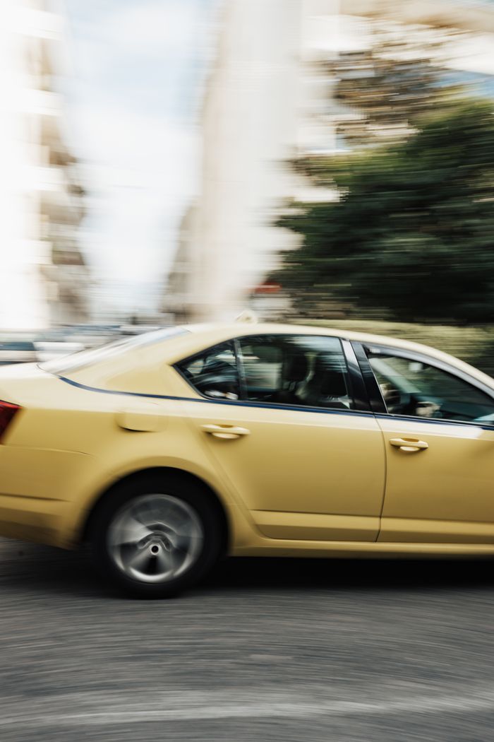 About Motion blur of a yellow car racing through an urban street, capturing speed and movement.