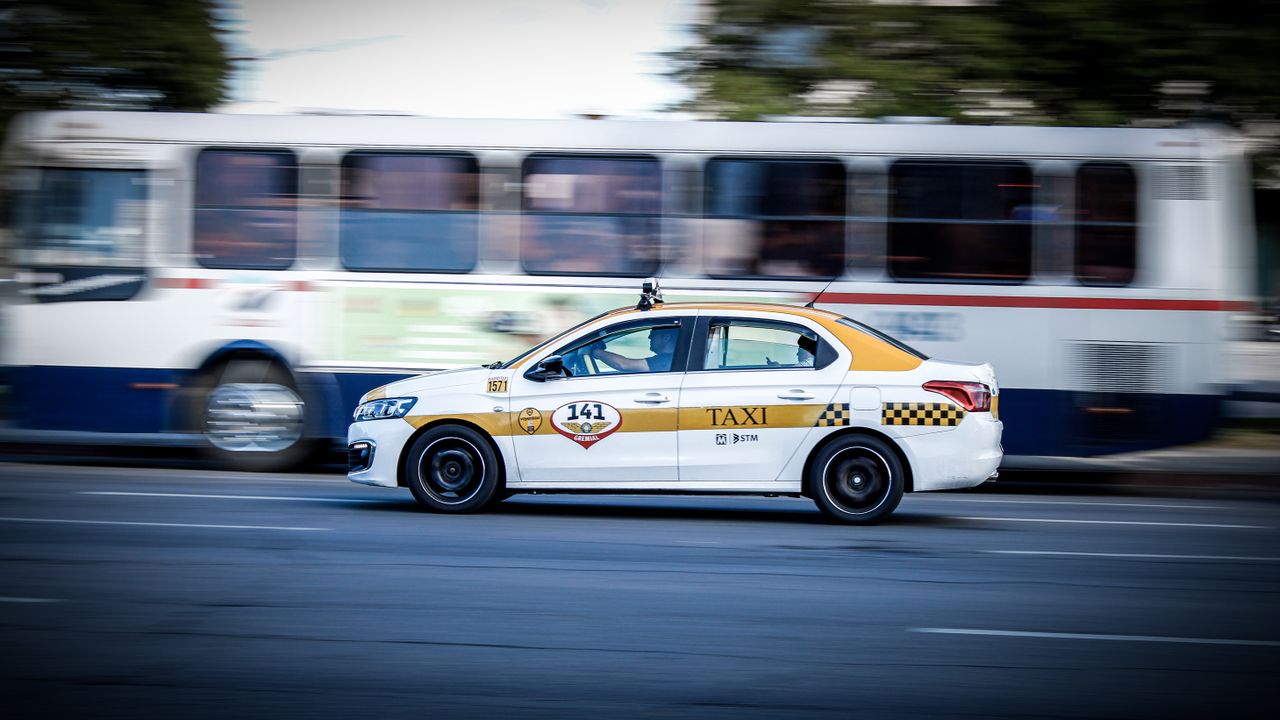 A yellow and white taxi speeding through Montevideo city streets, captured with motion blur effect.
